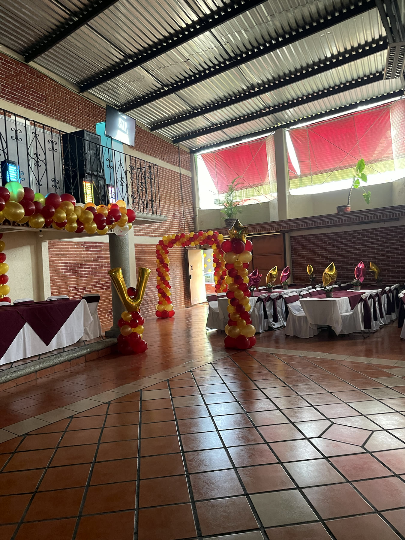 Arco de globos rojo y dorado en entrada de evento